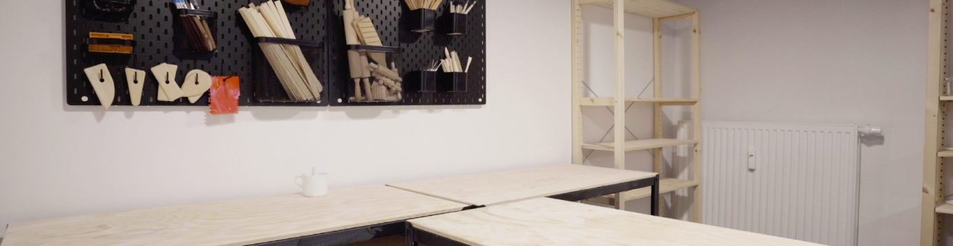 Werkstatt mit Holzpanelen, Regalen und einer Arbeitsfläche aus hellem Holz.